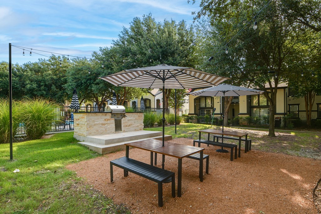 a picnic area with benches and umbrellas in a park