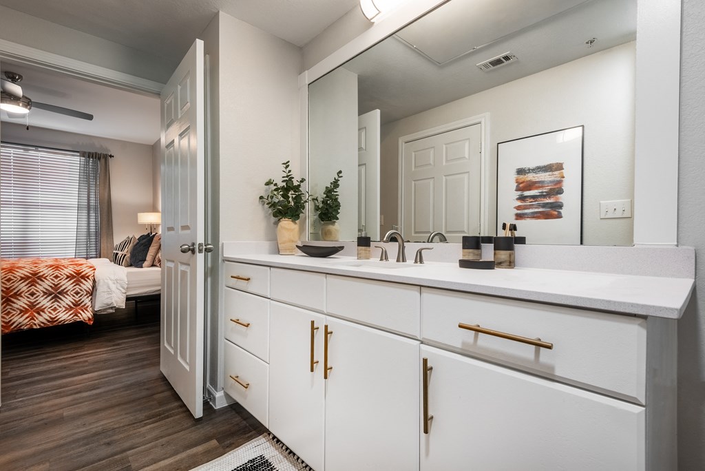 an open bathroom with a large mirror and white cabinets