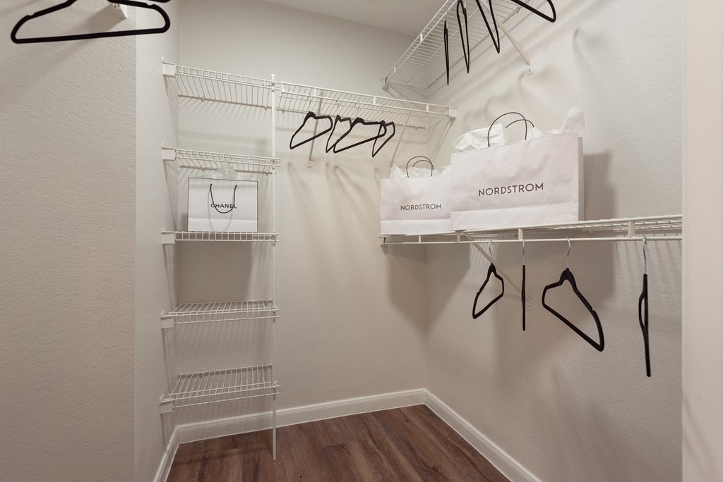 a walk in closet with bags and shoes on hanging racks