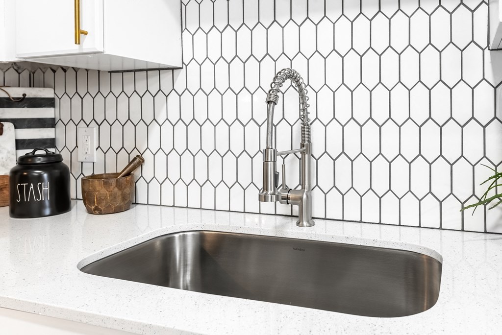 a stainless steel sink in a kitchen with black and white tiles