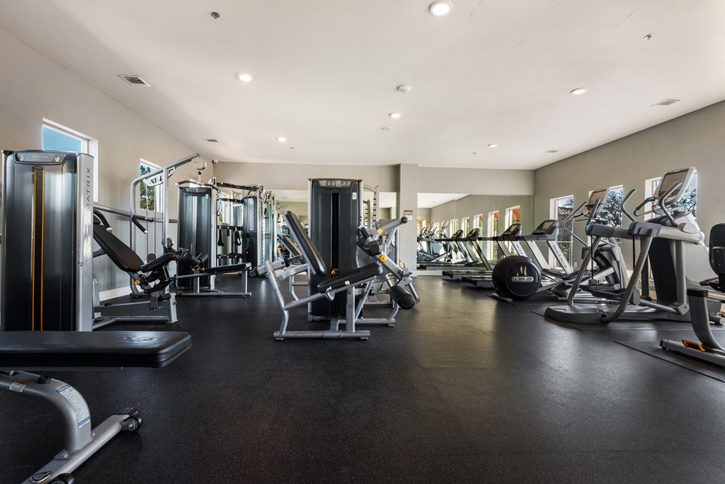 a large fitness room with cardio equipment and weights