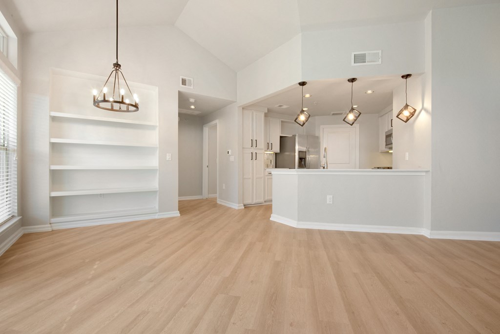 a spacious living room with a kitchen in the background