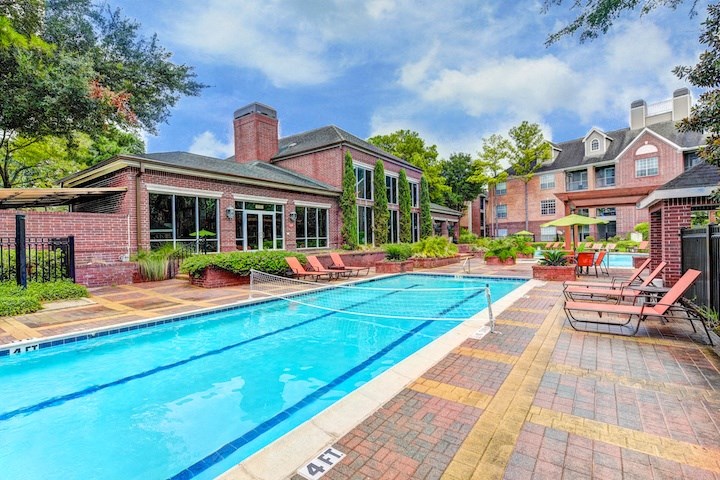A swimming pool with a brick building in the background.