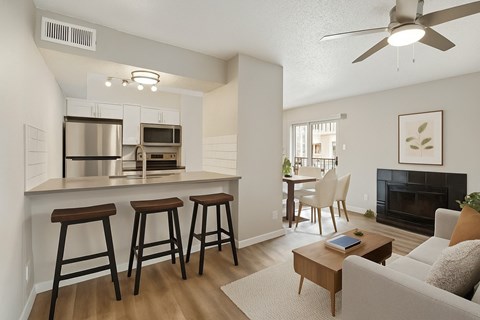A modern kitchen with a bar area and a living room with a fireplace.