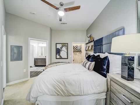 A bedroom with a large bed and a ceiling fan.