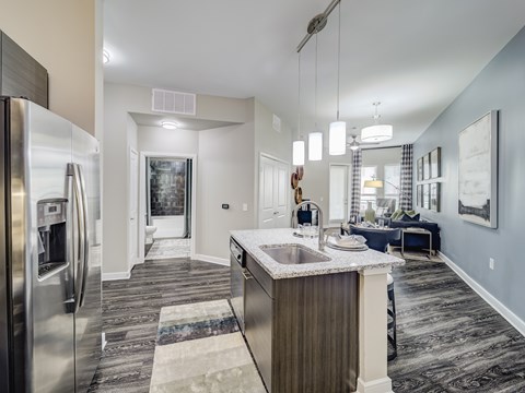 A modern kitchen with a stainless steel refrigerator and a marble countertop.