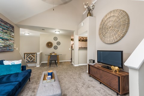 A living room with a blue couch and a wooden entertainment center.