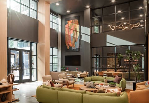 A modern living room with a green sofa and a large abstract painting on the wall.