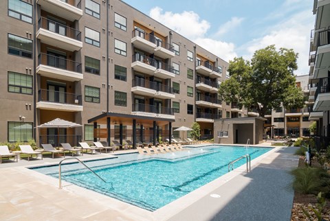 A large swimming pool is surrounded by apartment buildings.