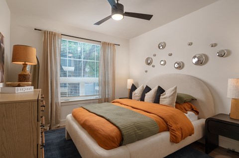 A bedroom with a bed, nightstand, and a ceiling fan.