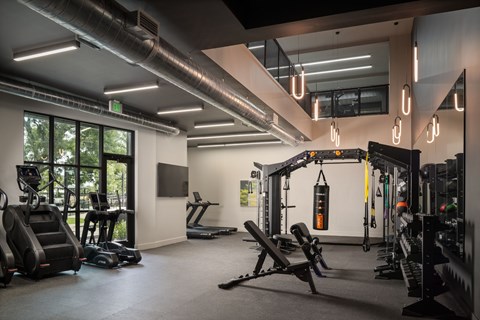 A gym with a variety of equipment including treadmills, weights, and exercise machines.
