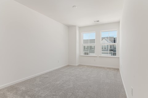 an empty living room with a large window and carpet