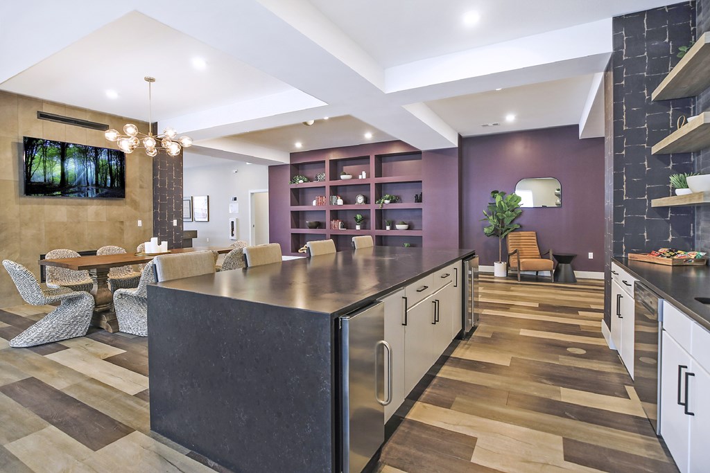 A modern kitchen with a black countertop and wooden flooring.