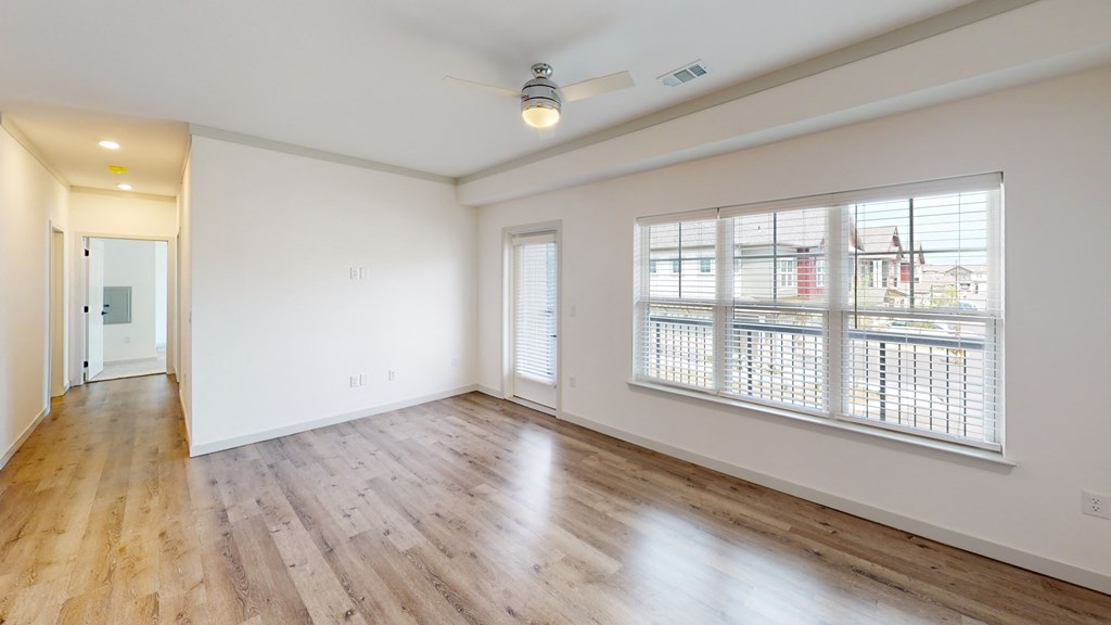an empty living room with hardwood floors and a ceiling fan