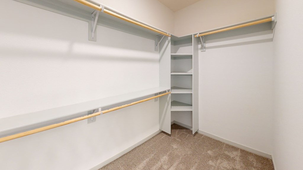 a walk in closet with a white wall and a white sliding door with a wooden handle