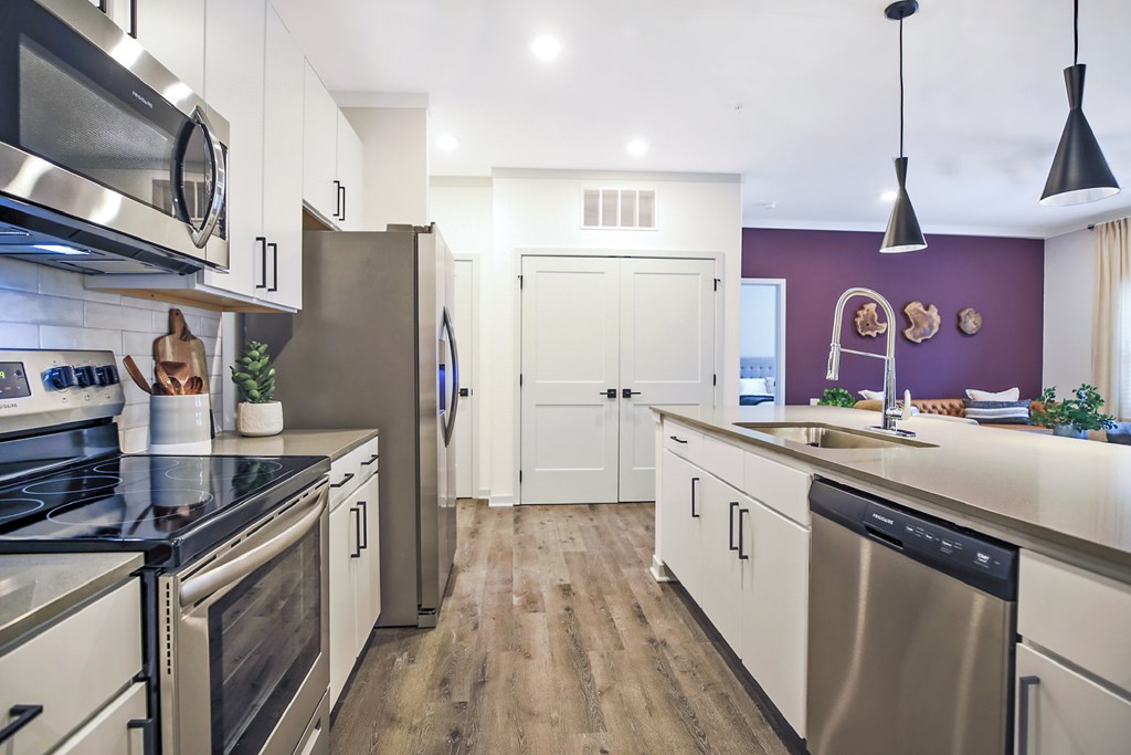 A modern kitchen with stainless steel appliances and wooden floors.