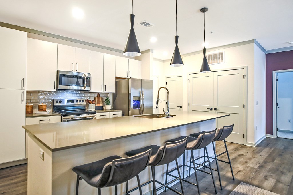 A kitchen with a long island and bar stools.