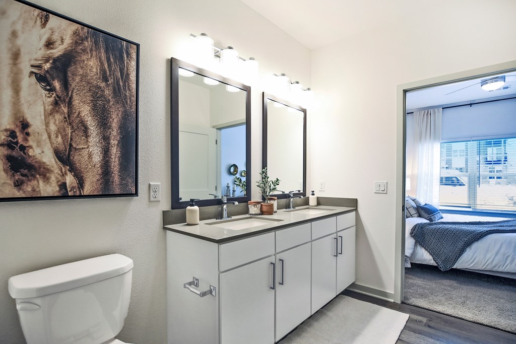 A bathroom with a white toilet, a large mirror, and a painting of a horse on the wall.
