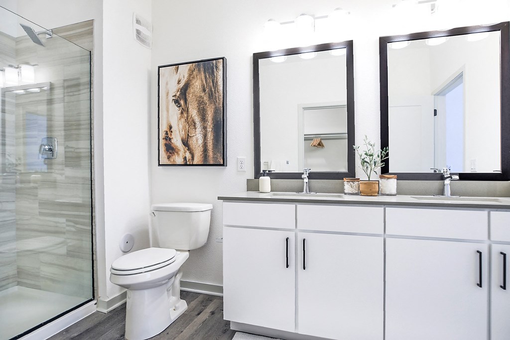 a bathroom with white cabinets and two mirrors