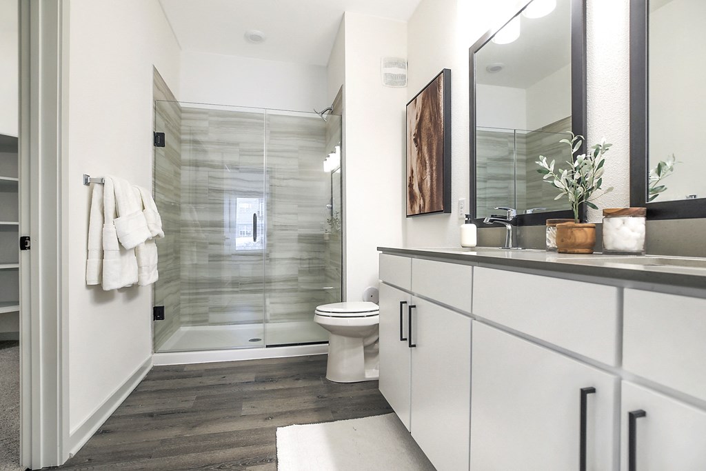 a bathroom with white cabinets and a glass shower