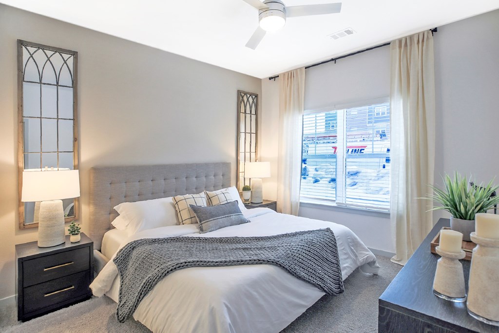 A bedroom with a large bed and a window overlooking a cityscape.