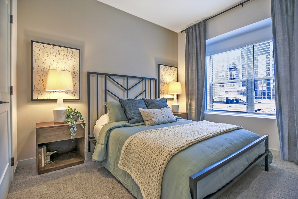 A bedroom with a bed, nightstand, and window.