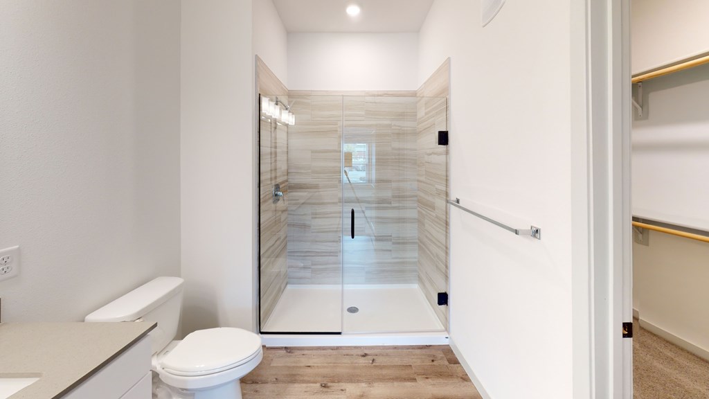 A white toilet is in a bathroom with a walk-in shower.