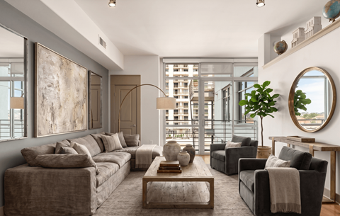A living room with a grey couch, a coffee table, and a large painting on the wall.