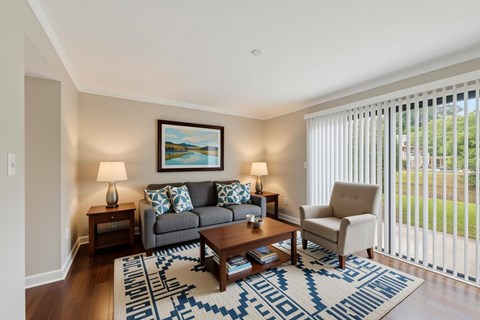 A living room with a grey couch, a coffee table, and a painting on the wall.