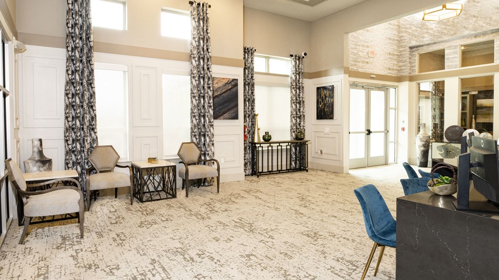 a living room with chairs and a table and a lobby with windows