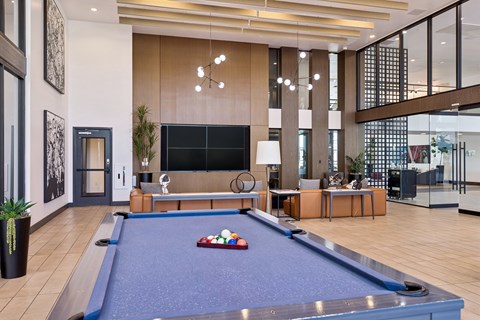 A pool table is in the middle of a room with a couch and a TV.