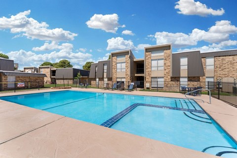A swimming pool in front of a building with a fence around it.