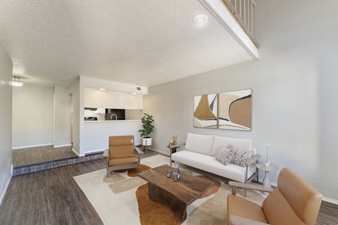 A living room with a white couch and brown chairs.