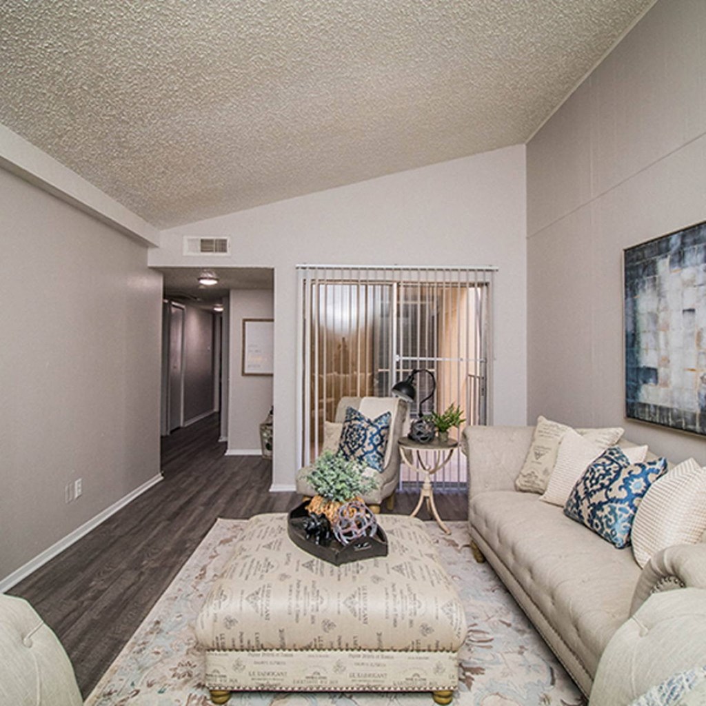 A living room with a couch, chair, and a table with a plant on it.