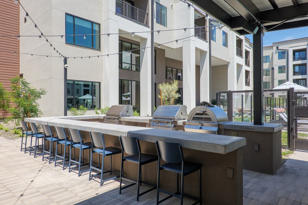 A long outdoor bar with stools is in front of a building.
