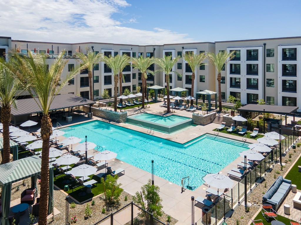 A large swimming pool surrounded by palm trees and lounge chairs.