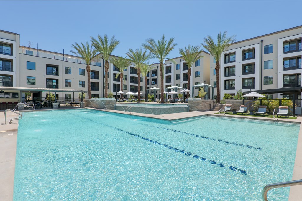 A large swimming pool in front of a building with palm trees.