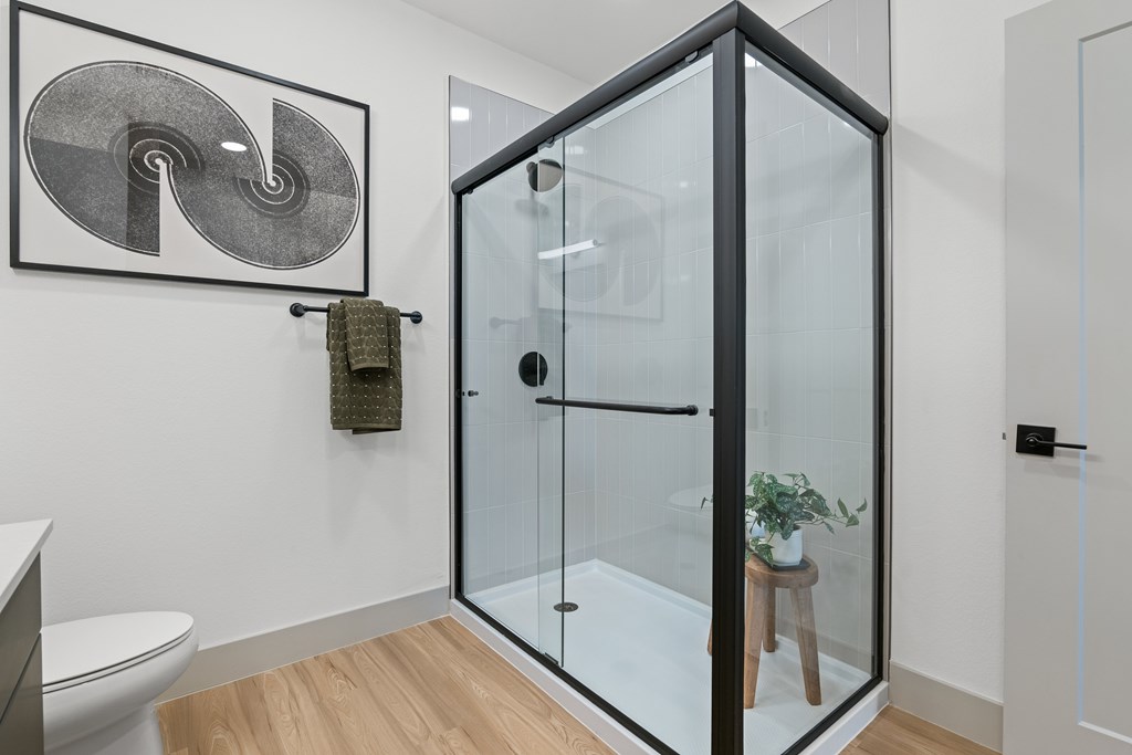 A bathroom with a glass shower enclosure and a toilet.