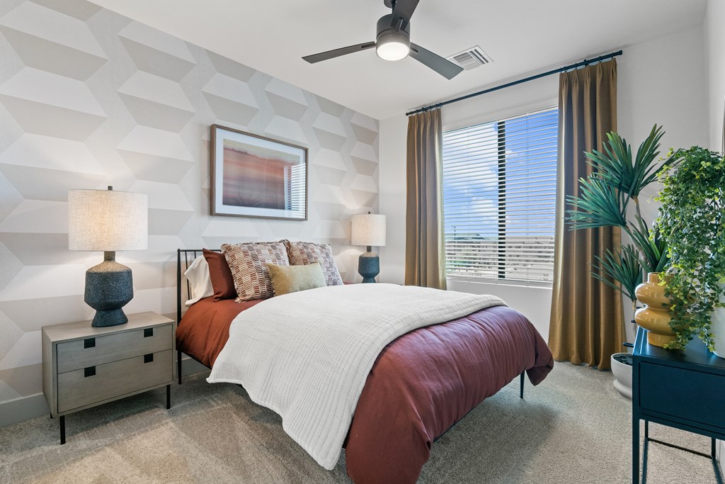 A bedroom with a bed, nightstands, and a ceiling fan.