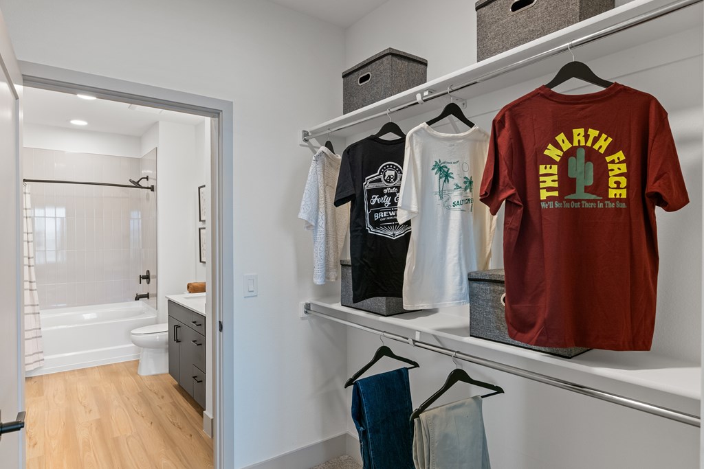 A closet into a bathroom with a red shirt with the words