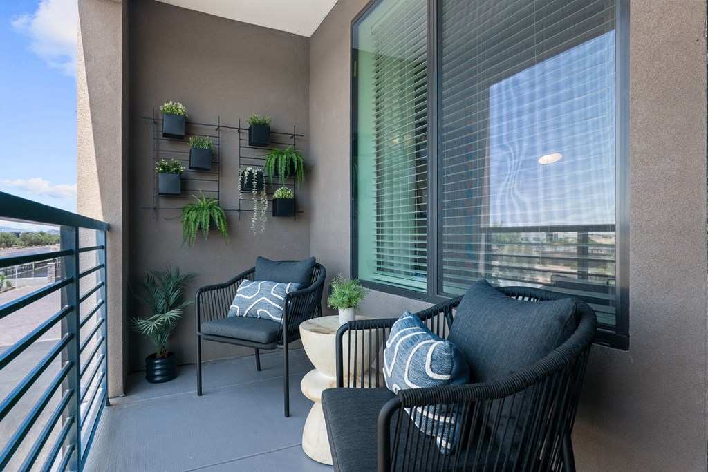 A balcony with two chairs and a table.