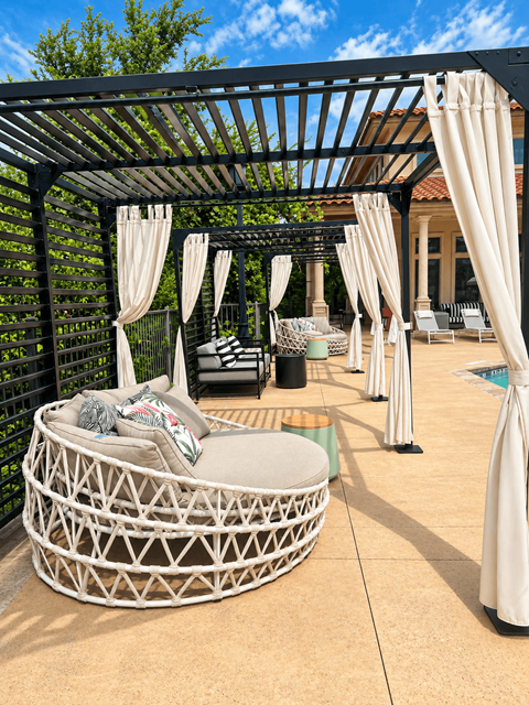 A white wicker sofa with a cushion and a pillow is on a patio.