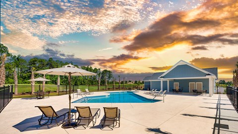 A poolside area with chairs and a house in the background.