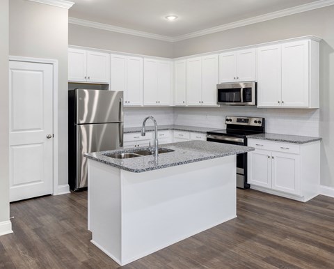 A kitchen with white cabinets and a granite countertop.