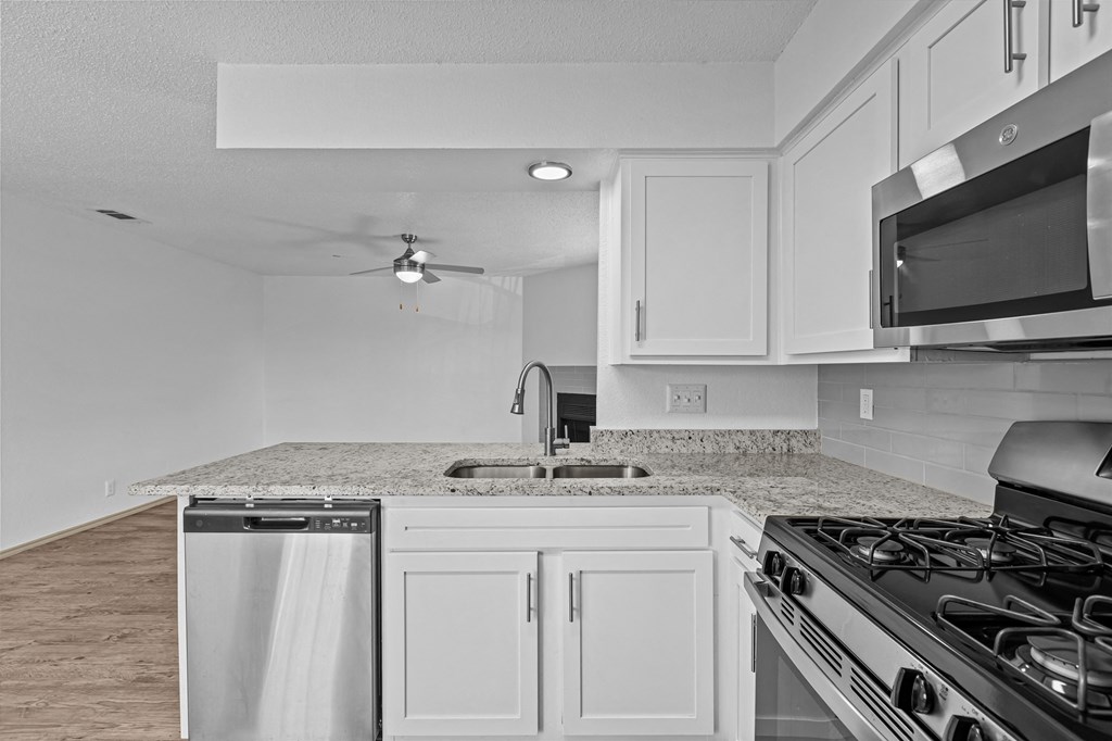 A kitchen with a stove, sink, and microwave.