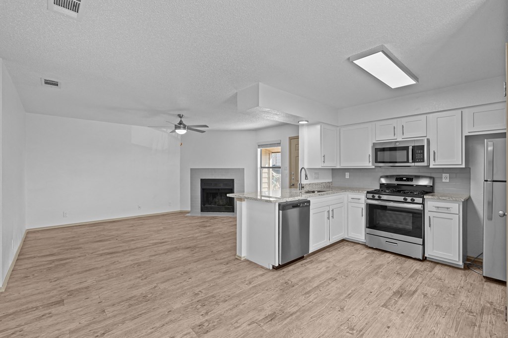 A spacious kitchen with a wood floor and white appliances.