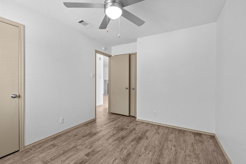 A room with a ceiling fan and wood flooring.