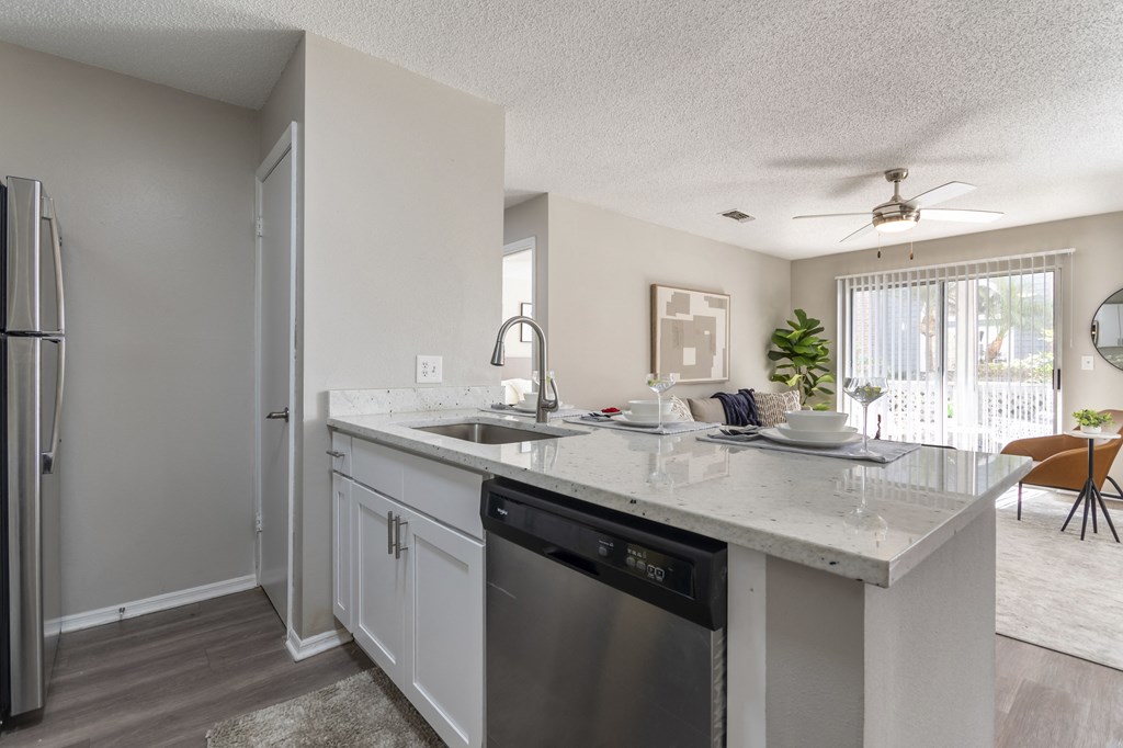 A kitchen with a white countertop and a stainless steel dishwasher.