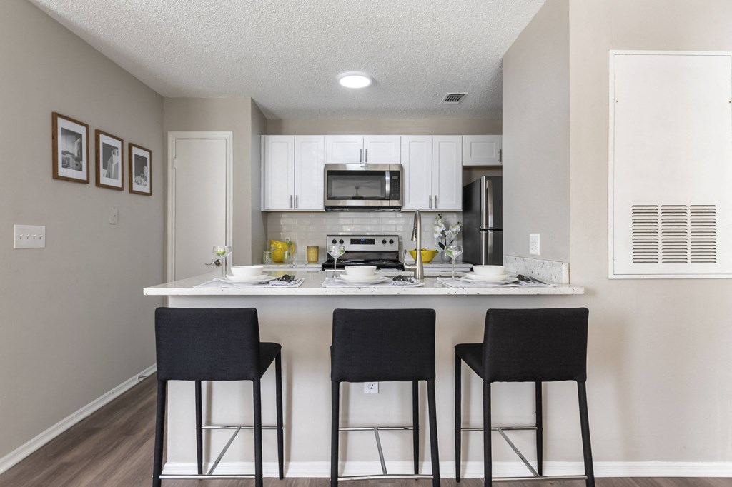 A kitchen with a table and chairs in front of it.