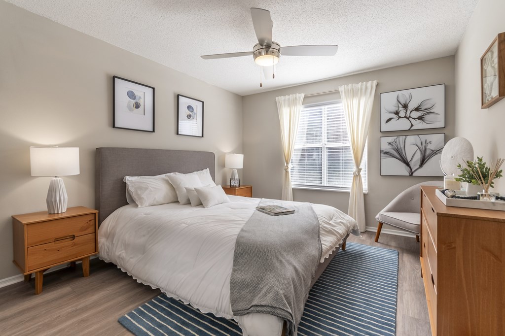 A bedroom with a bed, nightstand, and a ceiling fan.
